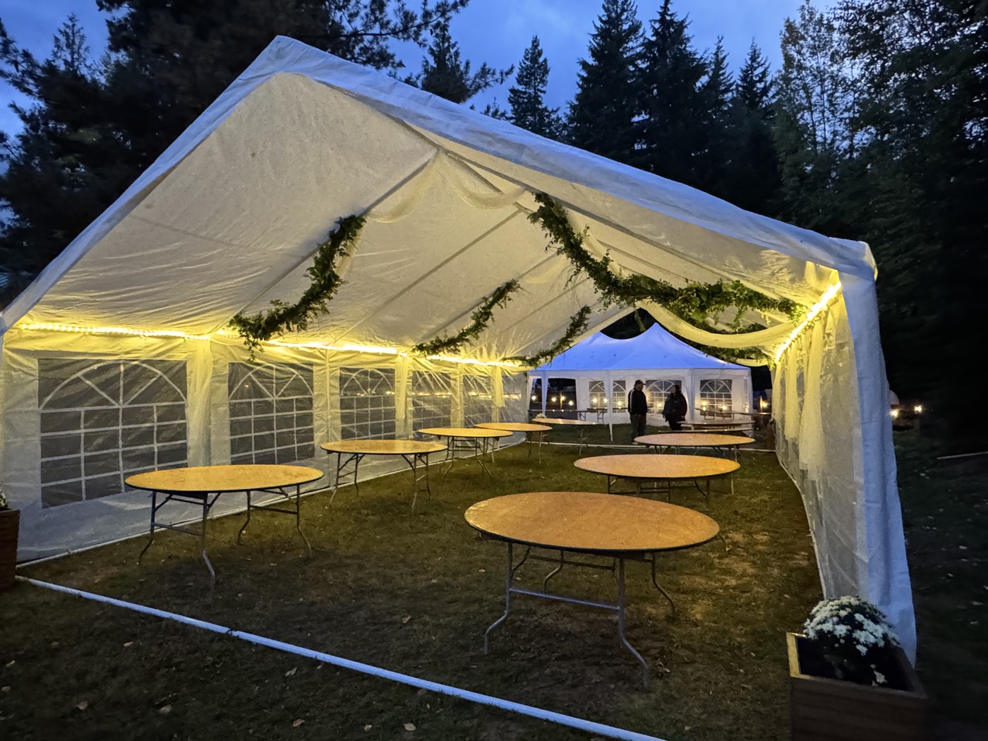 Wedding tent with garlands and warm string lights at dusk
