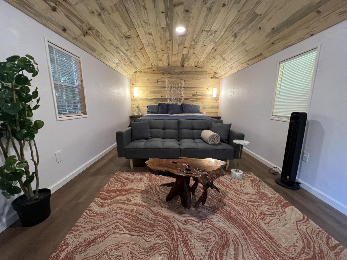 A cabin living area with a wood-panelled ceiling and forest views
