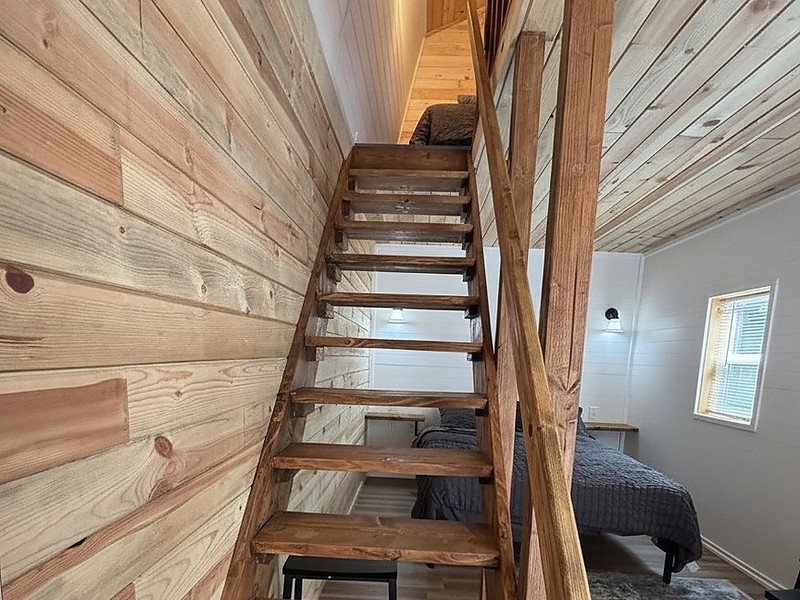The timber loft stair inside The Caribou, running up the cedar plank wall to the twin beds under the curved ceiling